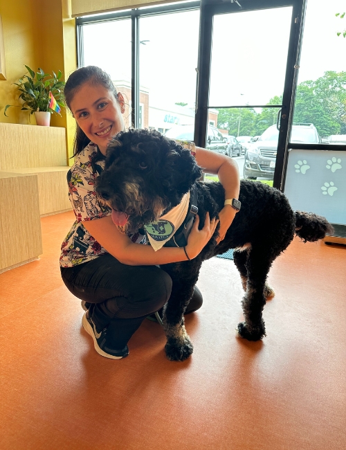 The woman is holding a black dog